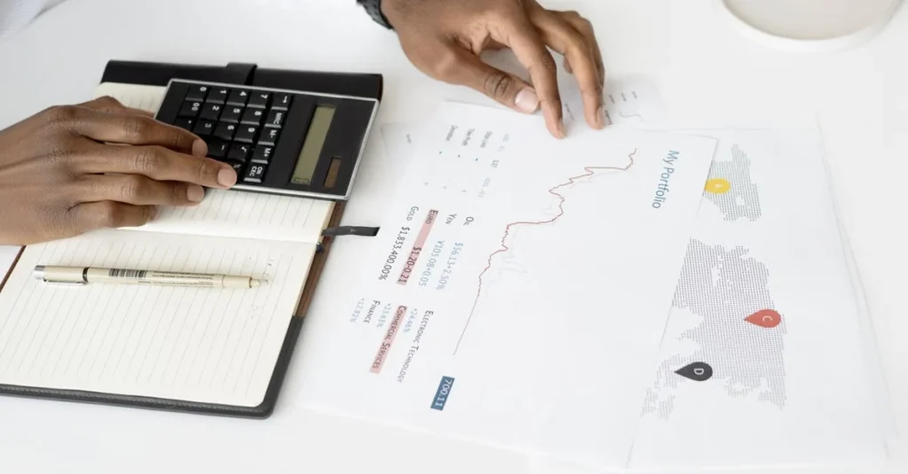 Person analyzing modash alternatives using calculator and financial charts on white desk workspace.