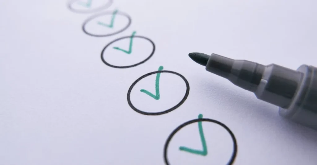 Close-up of a black marker beside a paper checklist, with teal checkmarks inside hand-drawn circles, conveying completion and organization.