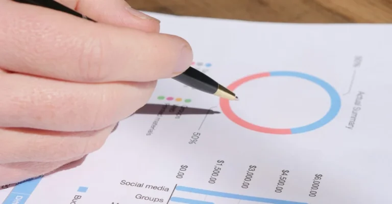 Hand pointing to social media metrics on chart tracking brand mentions and engagement data.