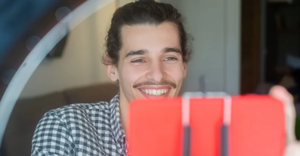 Man smiling at desk with red brandwatch alternatives analytics display visible.
